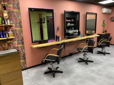 Drie kappersstoelen voor zwarte spiegels aan de oudroze wand