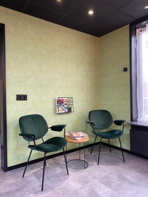 Wachthoek met twee donkergroene fauteuils tegen een saliegroene wand